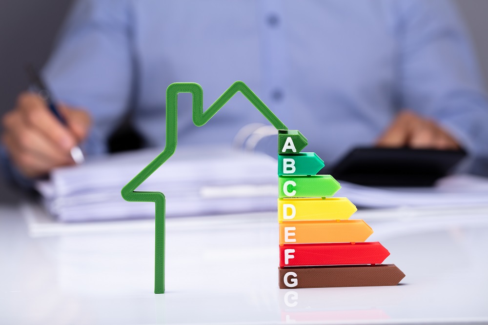 Pyramide du classement du diagnostic de performance énergétique complété avec une maison symbolisant l'audit énergétique.