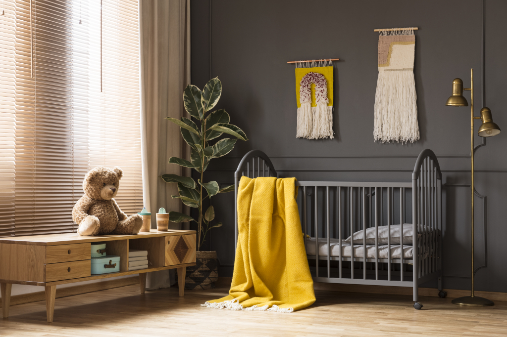 Chambre d'enfant murs foncés sol en parquet et couverture jaune