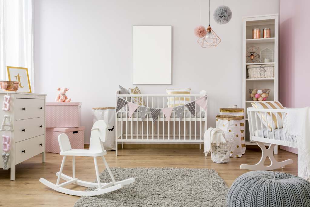 chambre de bébé décorée en rose avec cheval à bascule, tapis, commode et pouf
