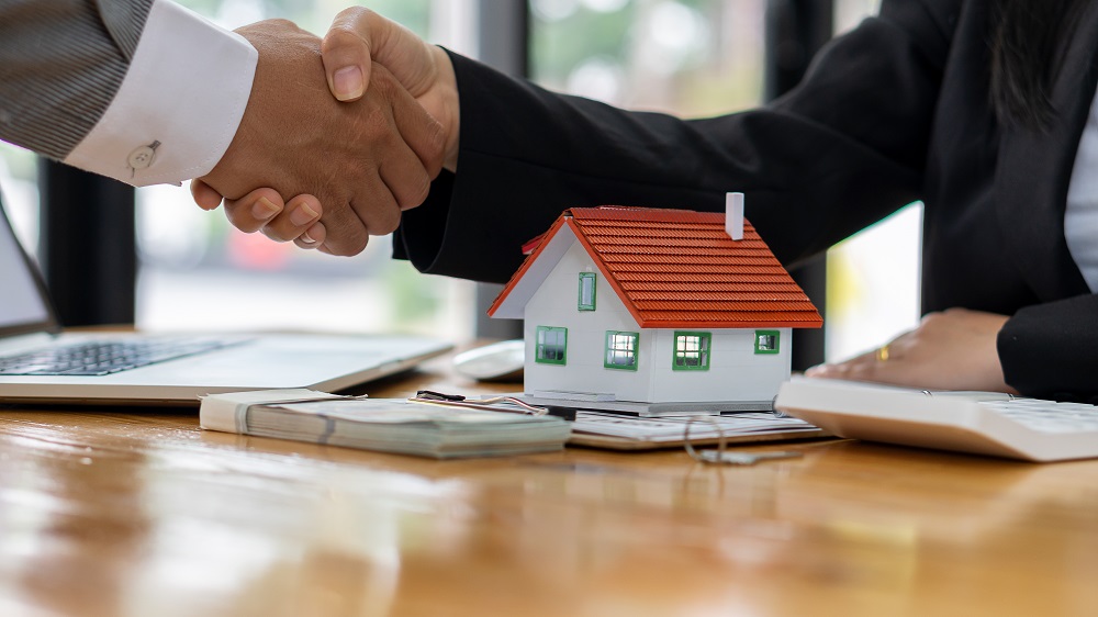 Un courtier en immobilier et un acheteur se serrent la main en signe d'accord pour le crédit. 